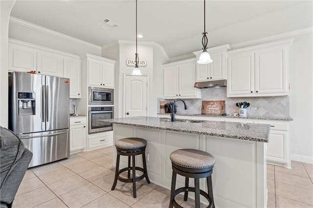 kitchen with a center island with sink, light stone counters, light tile patterned flooring, white cabinetry, and stainless steel appliances