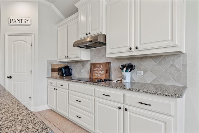 kitchen with light stone counters, light tile patterned flooring, white cabinetry, black electric cooktop, and decorative backsplash