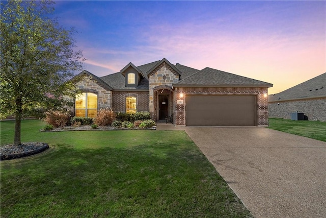 french provincial home featuring a garage and a yard