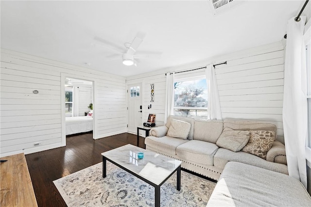 living room featuring wood walls, ceiling fan, and dark hardwood / wood-style floors