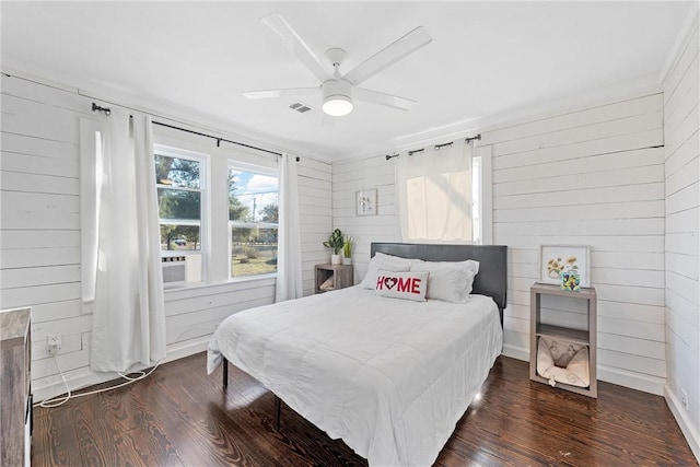 bedroom featuring ceiling fan, wood walls, and dark hardwood / wood-style flooring