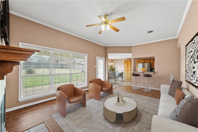 living room with hardwood / wood-style floors, crown molding, and ceiling fan