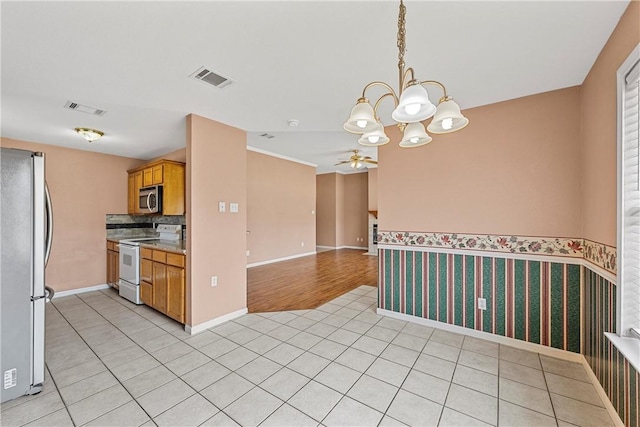 kitchen with light tile patterned floors, ceiling fan with notable chandelier, and appliances with stainless steel finishes