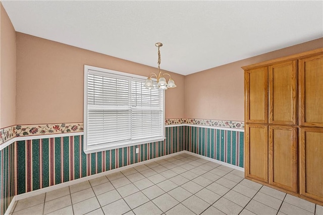 tiled spare room with an inviting chandelier