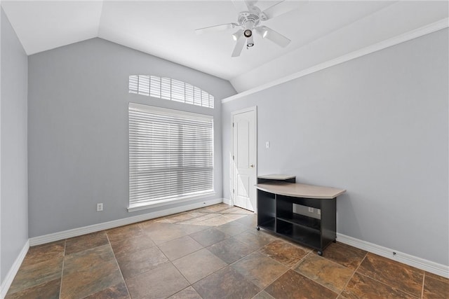 empty room with vaulted ceiling, stone tile floors, and baseboards