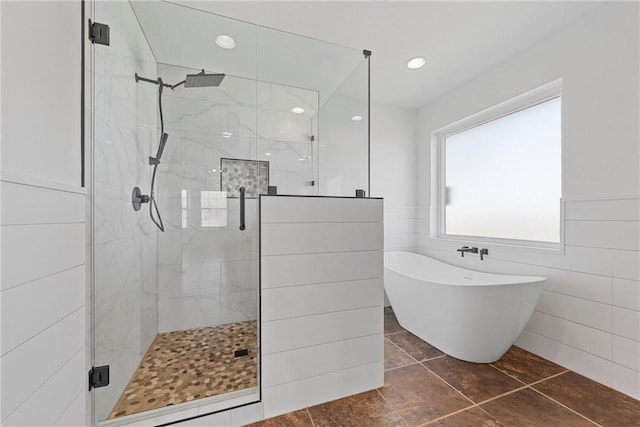 bathroom with a stall shower, a freestanding tub, and tile walls