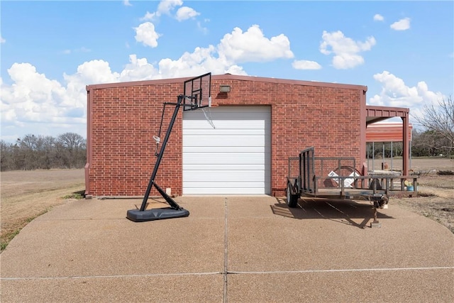 view of side of property featuring a garage, concrete driveway, and brick siding