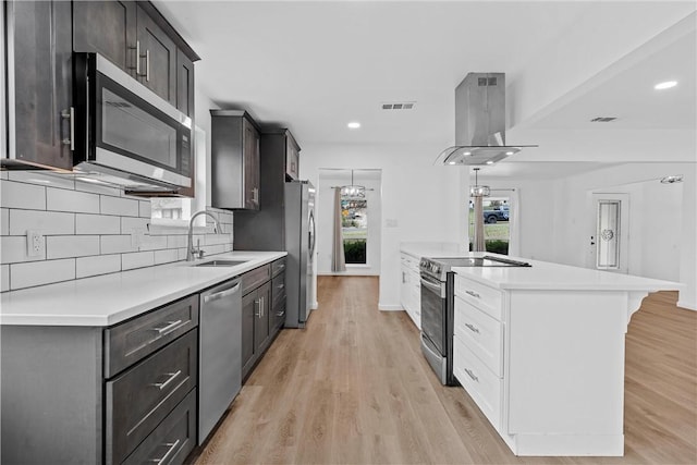 kitchen with decorative backsplash, stainless steel appliances, sink, wall chimney range hood, and light hardwood / wood-style flooring