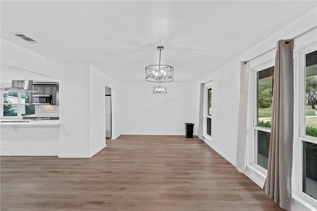 corridor with hardwood / wood-style flooring and an inviting chandelier