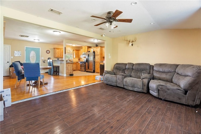 living room featuring ceiling fan, hardwood / wood-style floors, and vaulted ceiling