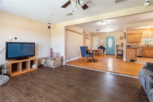 living room with dark hardwood / wood-style flooring, ceiling fan, and sink