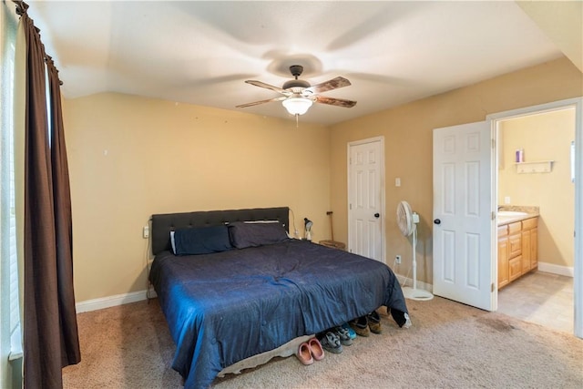 bedroom featuring ceiling fan, ensuite bathroom, lofted ceiling, and light carpet