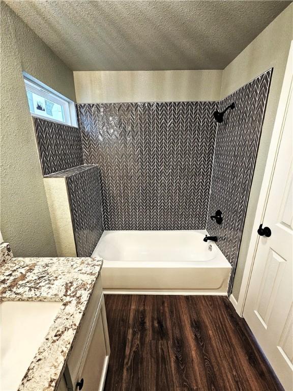 bathroom featuring a textured ceiling, tiled shower / bath combo, wood-type flooring, and vanity