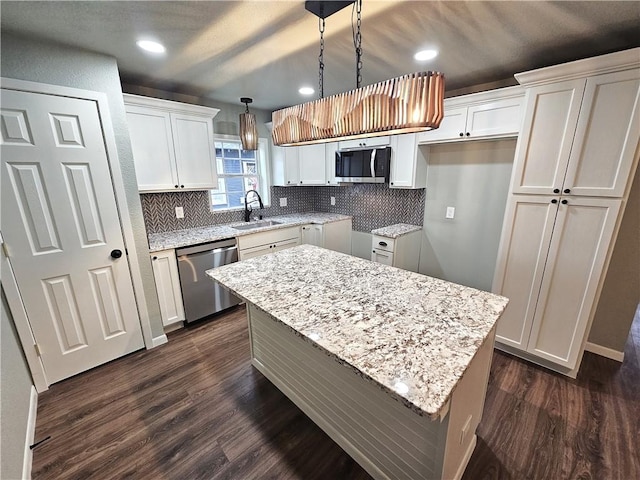 kitchen with appliances with stainless steel finishes, a center island, pendant lighting, white cabinets, and sink