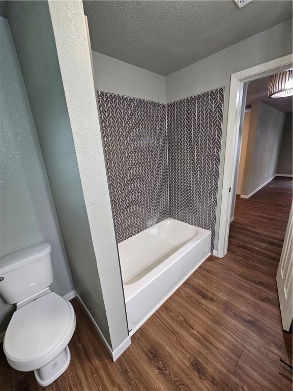 bathroom featuring toilet, a shower, a textured ceiling, and hardwood / wood-style flooring