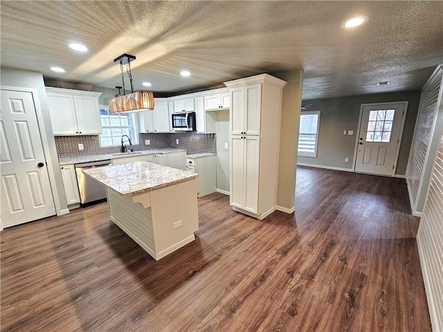 kitchen featuring decorative light fixtures, white cabinets, stainless steel appliances, and a center island