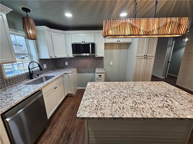 kitchen featuring appliances with stainless steel finishes, white cabinets, a kitchen island, and sink