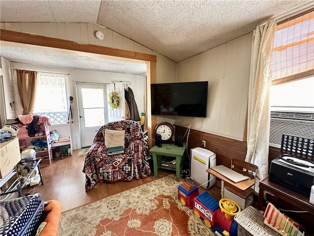 rec room featuring hardwood / wood-style floors, a textured ceiling, lofted ceiling, and wood walls