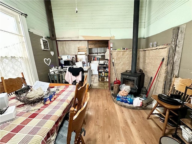 dining room featuring a wood stove, a towering ceiling, and light hardwood / wood-style floors