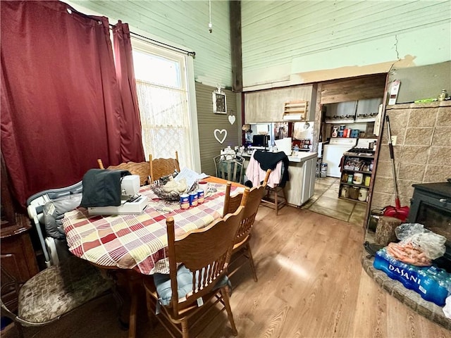 dining room featuring wooden walls, light hardwood / wood-style floors, and a high ceiling