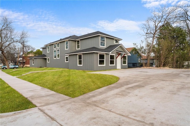 view of front of home featuring driveway, roof with shingles, and a front lawn