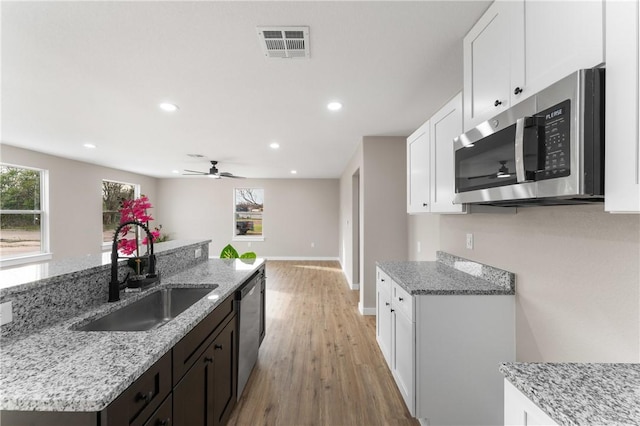 kitchen with light stone countertops, visible vents, a sink, stainless steel appliances, and white cabinets