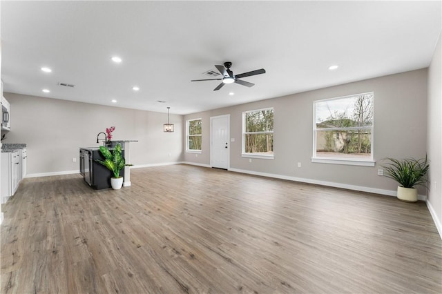 unfurnished living room with light wood-style flooring, recessed lighting, a ceiling fan, and baseboards