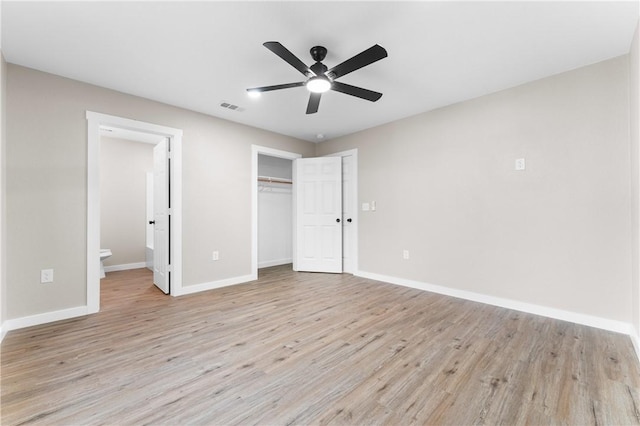 unfurnished bedroom with light wood-type flooring, visible vents, a closet, connected bathroom, and baseboards