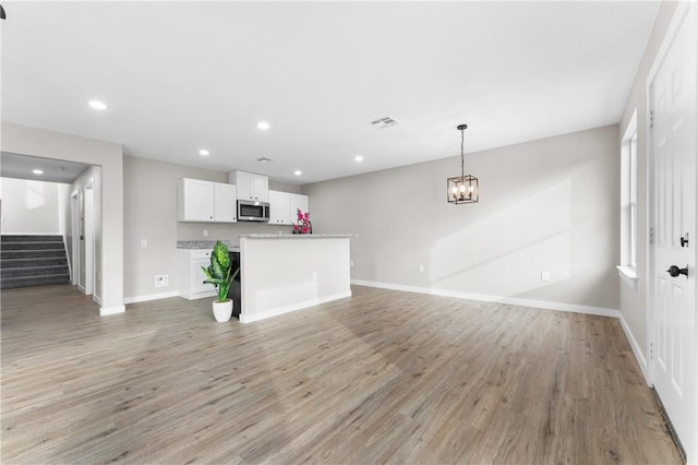 unfurnished living room with stairs, light wood-style flooring, and recessed lighting