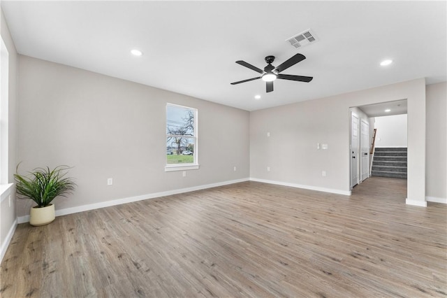 empty room with stairs, light wood-style flooring, baseboards, and visible vents