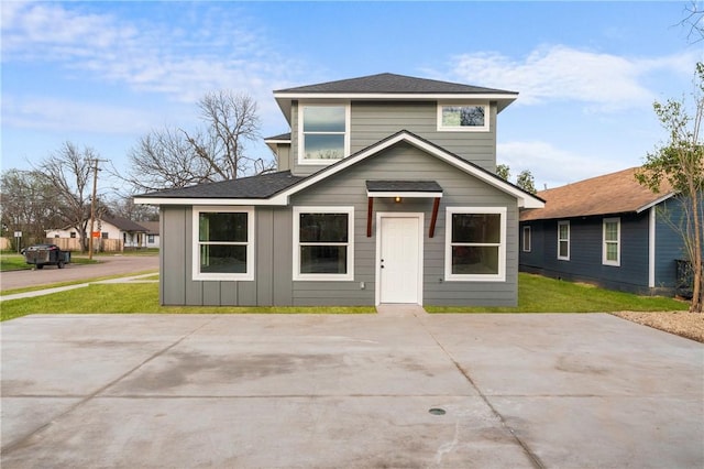 view of front facade featuring a front lawn and a shingled roof