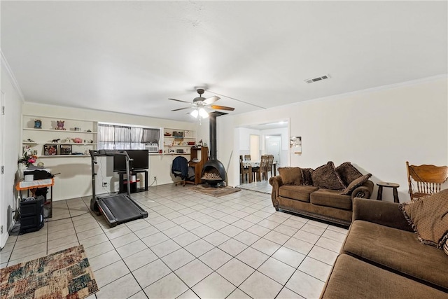 tiled living room with a wood stove, ceiling fan, and ornamental molding