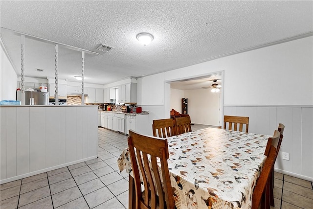 tiled dining space with ceiling fan and a textured ceiling