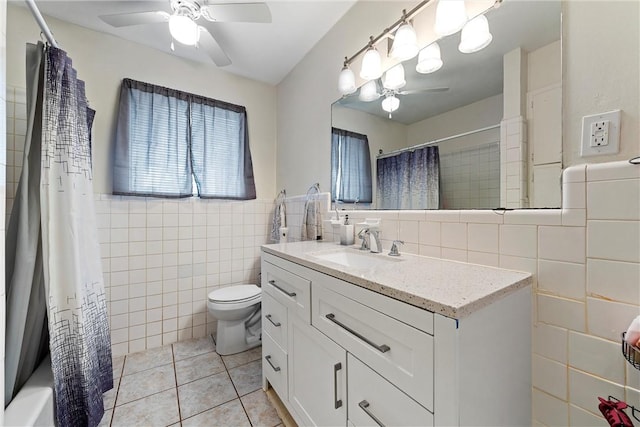 full bathroom featuring vanity, shower / bathtub combination with curtain, tile walls, tile patterned flooring, and toilet