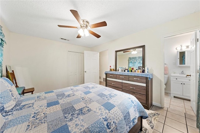 bedroom featuring connected bathroom, ceiling fan, a textured ceiling, a closet, and light tile patterned floors