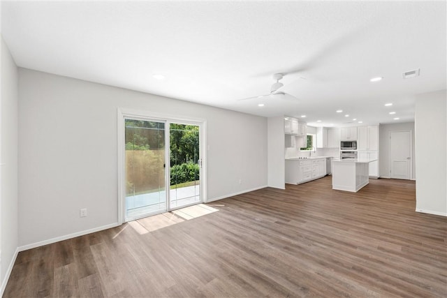 unfurnished living room featuring ceiling fan and dark hardwood / wood-style flooring