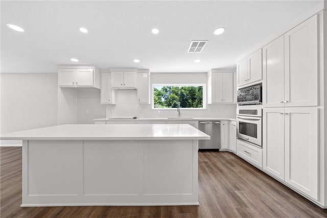 kitchen with hardwood / wood-style floors, a center island, sink, white cabinetry, and stainless steel appliances