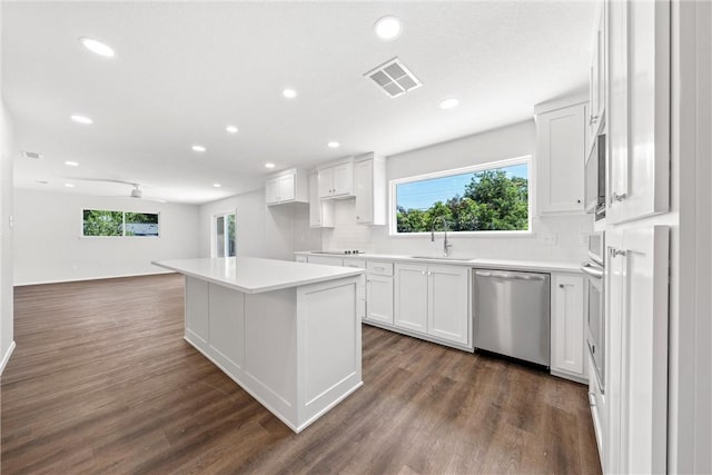 kitchen with dishwasher, sink, dark wood-type flooring, a kitchen island, and white cabinets