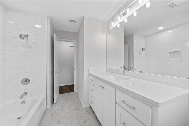 bathroom with tiled shower / bath combo and vanity