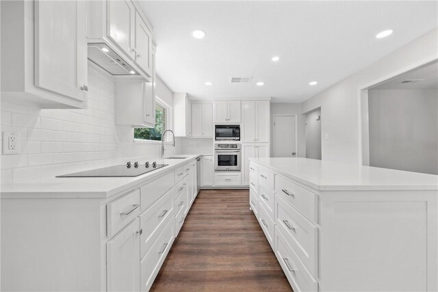 kitchen with dark wood-type flooring, sink, black appliances, a center island, and white cabinetry