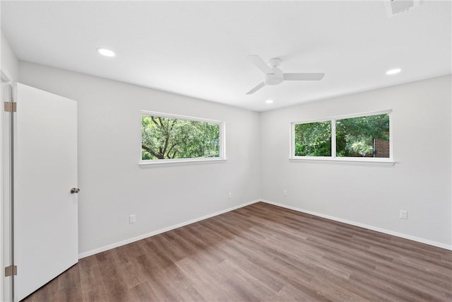 empty room with ceiling fan, a healthy amount of sunlight, and wood-type flooring