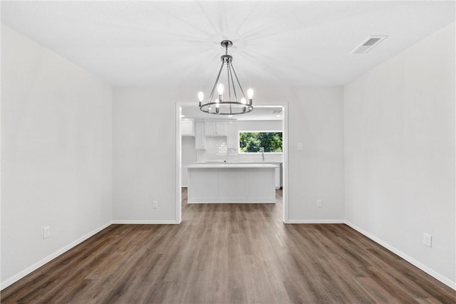 unfurnished dining area featuring dark hardwood / wood-style floors and an inviting chandelier