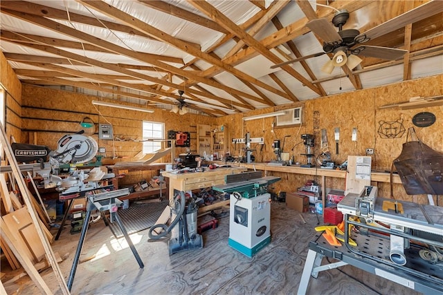 garage featuring a workshop area, ceiling fan, a wall mounted AC, and wood walls