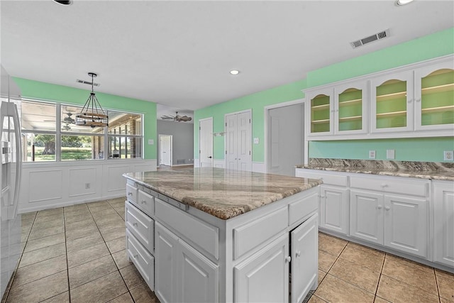 kitchen with ceiling fan, pendant lighting, white cabinets, a kitchen island, and light tile patterned flooring