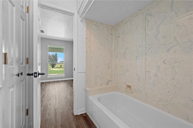 bathroom with a bath, wood-type flooring, and a textured ceiling