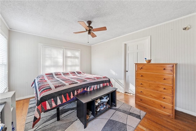 bedroom with a textured ceiling, light wood-type flooring, ceiling fan, and ornamental molding