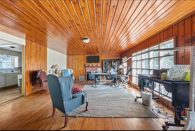 living area with a fireplace, light hardwood / wood-style floors, wooden ceiling, and wood walls