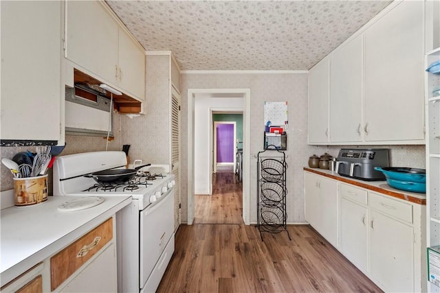 kitchen featuring light hardwood / wood-style floors, white cabinetry, crown molding, and gas range gas stove