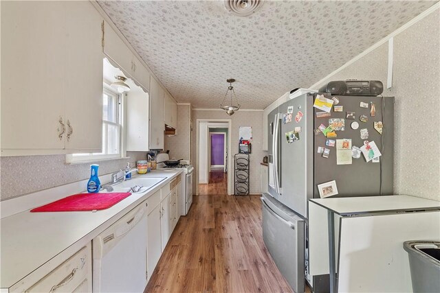 kitchen with white cabinets, white appliances, light hardwood / wood-style floors, and sink