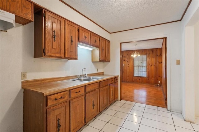 kitchen featuring sink, light tile patterned floors, a textured ceiling, decorative light fixtures, and a chandelier